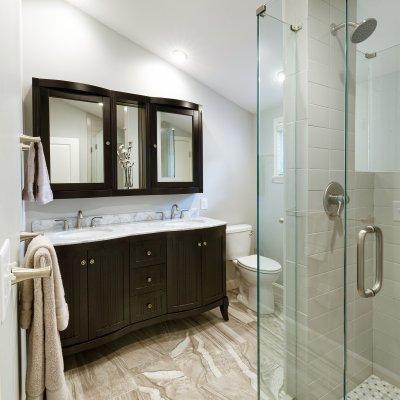 Bathroom with glass shower, black vanity, and mirror sloped ceiling   